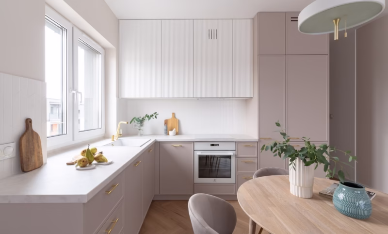 Bright kitchen with gold handles, white cabinets and a wooden worktop.