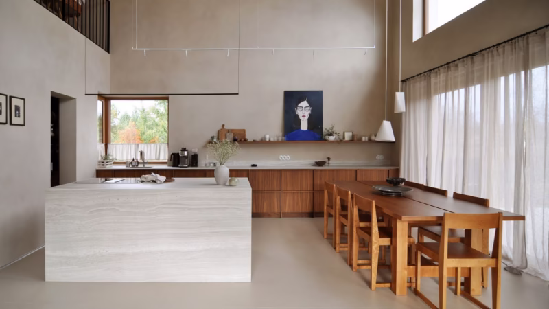 High ceiling, light kitchen with wooden cabinetry, a white island, a painting on the wall.