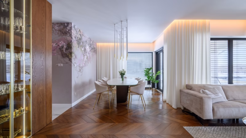 Atmospheric living room with dining area, flowering mural, wooden parquet and gold chair legs.