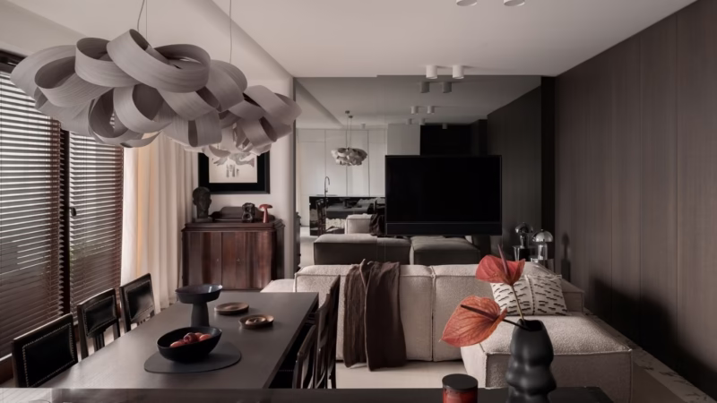 Modern living room with dark wood, a light sofa and a designer chandelier.