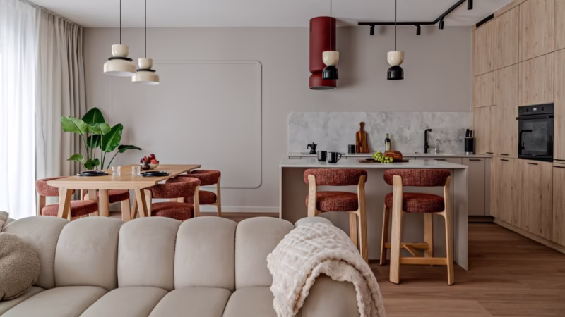 Spacious interior with a kitchen and dining area; wooden furniture, red stools.