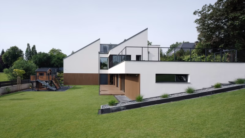 Detached house with a white façade, a terrace and a large lawn.