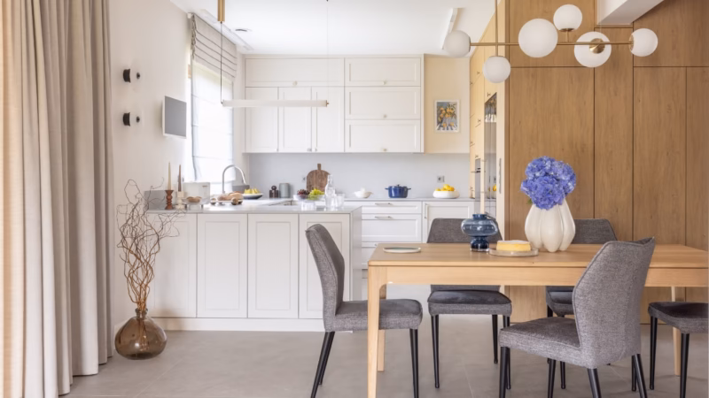 Light kitchen with wooden cabinetry and a table with chairs.