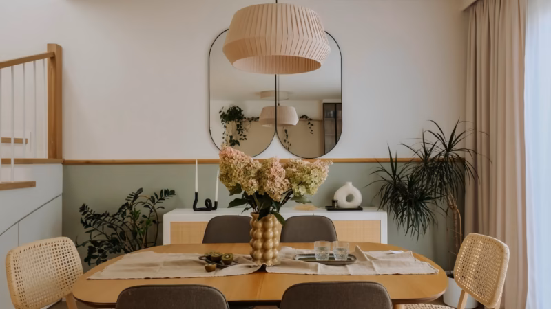 A dining room with a large mirror, plants and a bouquet of hydrangeas on the table