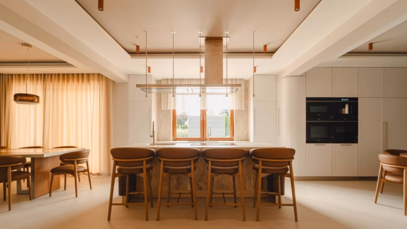 Kitchen with a stone island and four brown bar stools