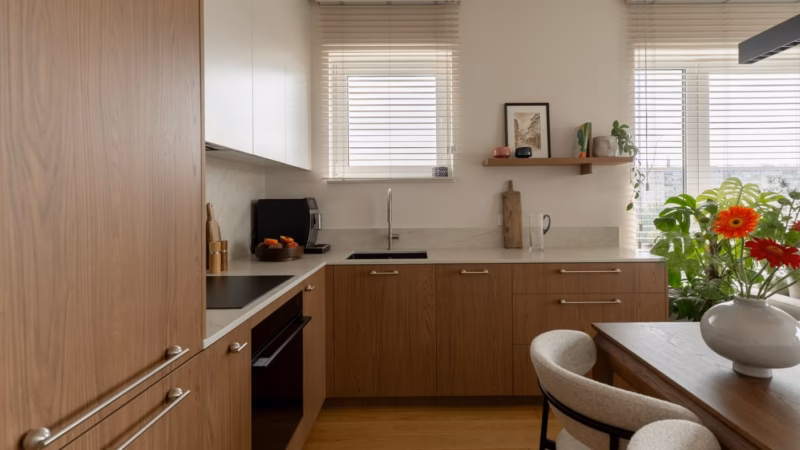 Kitchen with wooden built-in units, a light worktop and plants by the window