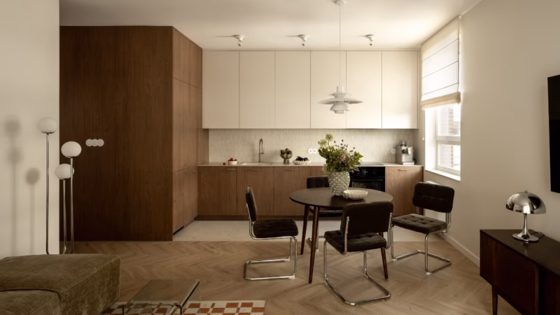 A kitchen with wooden fitted units and a round table with dark chairs