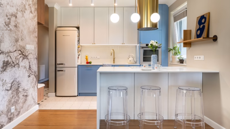 Blue and white kitchen with an island, a gold extractor hood and three bar stools