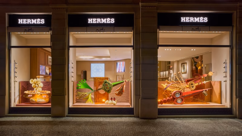 Three Hermès shop windows with colourful artistic compositions.